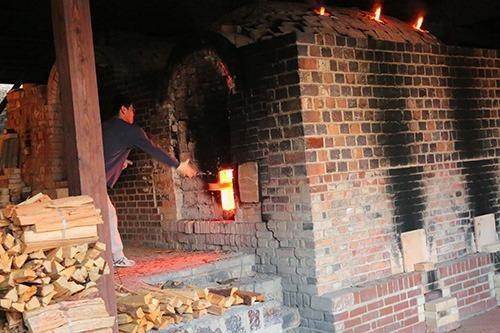 写真：様々な色味のレンガが使われた柿右衛門窯と、窯に薪をくべる男性の写真