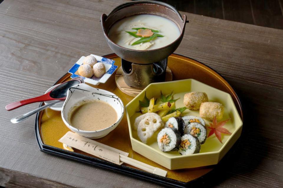 写真：手前左に湯豆腐のごまだれ、手前右に海苔巻き、奥にひとり用鉄鍋に入った湯豆腐があるセット料理