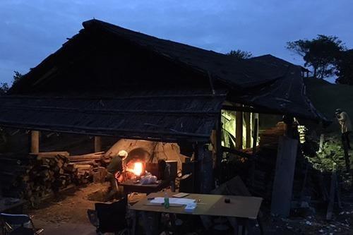 写真：小屋の中にある、天狗谷窯の中に薪をくべる男性の写真