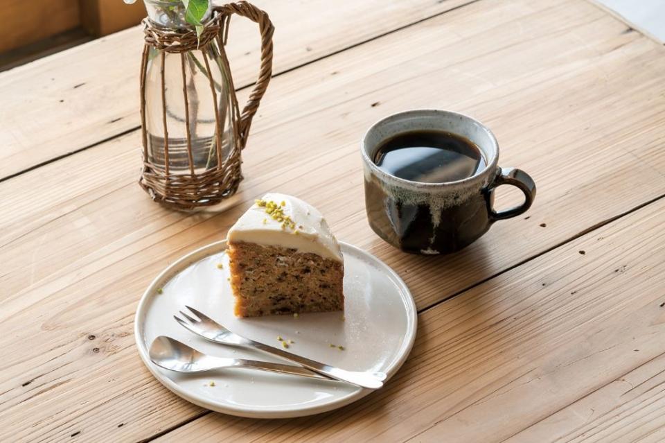 写真：コーヒーカップと素朴なケーキが木製テーブルの上にある様子