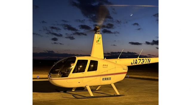 写真：日が沈みかけた空を背景に空港で駐機しているヘリコプター