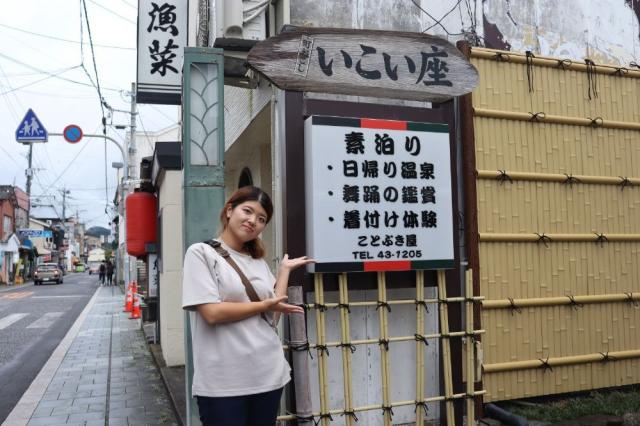 写真：いこい座入り口にの看板を示している女性ライター