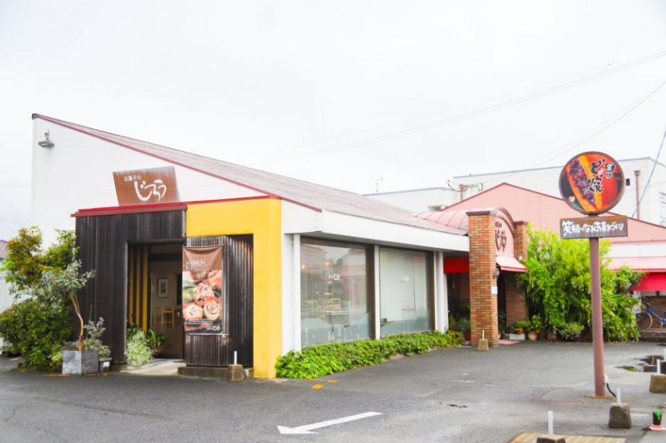 写真：店舗外観。入口が2カ所にあり、それぞれに「お菓子のじろう」のロゴ看板がついている。手前に「黒糖どら焼き」の標識風看板が立っている