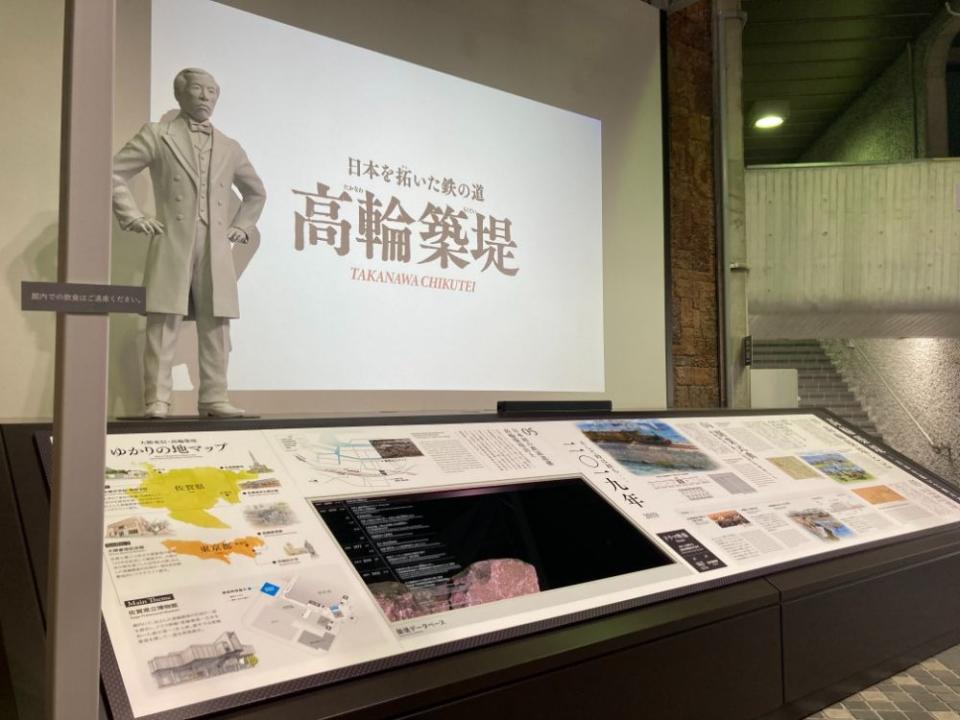 写真：高輪築堤の展示。大隈重信の立像とパネル展示、遺構の一部が展示されている