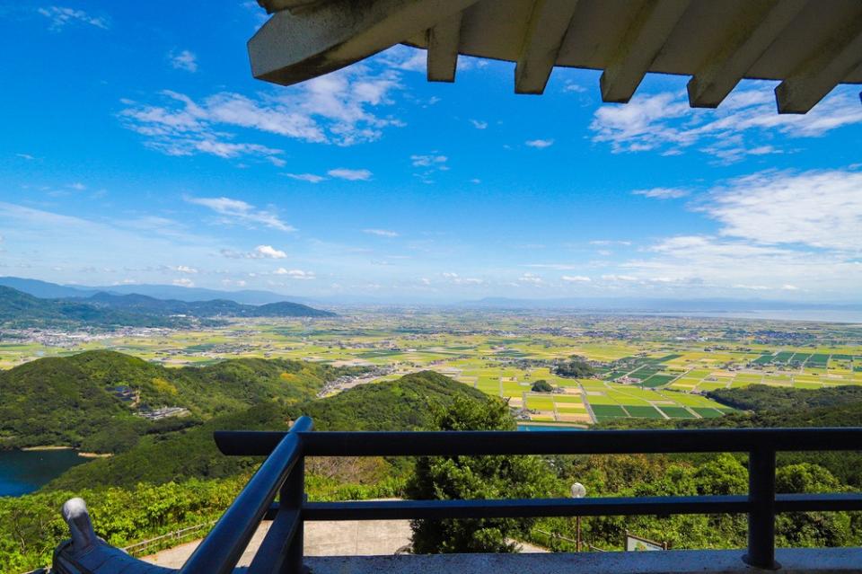 写真：手前に展望台の軒と手すりが写り込んだ佐賀平野と青空を望む風景