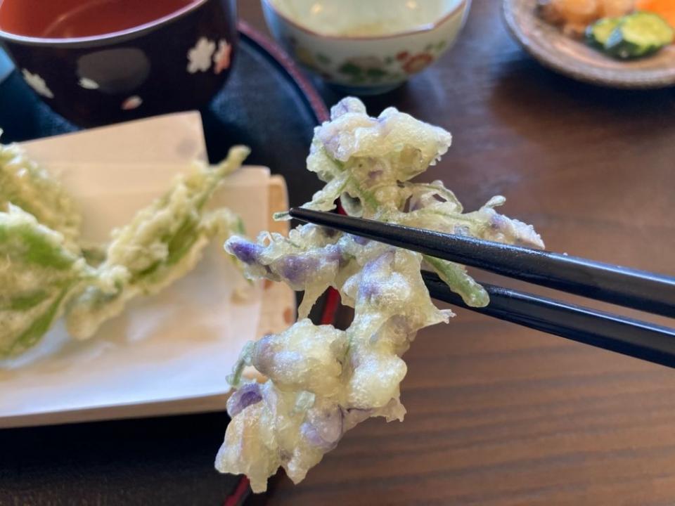 写真：藤の花の天ぷらを箸でつかんでいる様子