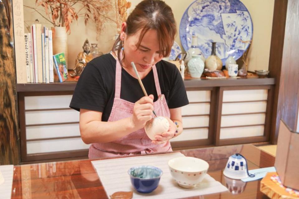 写真：素焼きの素材に絵付けしているエプロン姿の女性