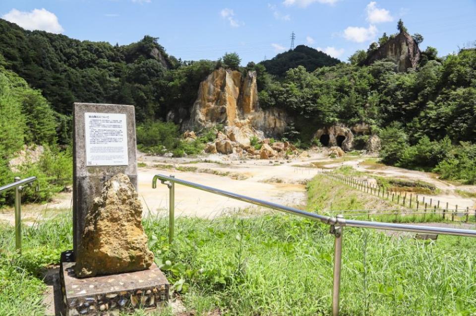 写真：泉山磁石場を見おろす高台にある陶石の説明板。高台には手すりがついている。