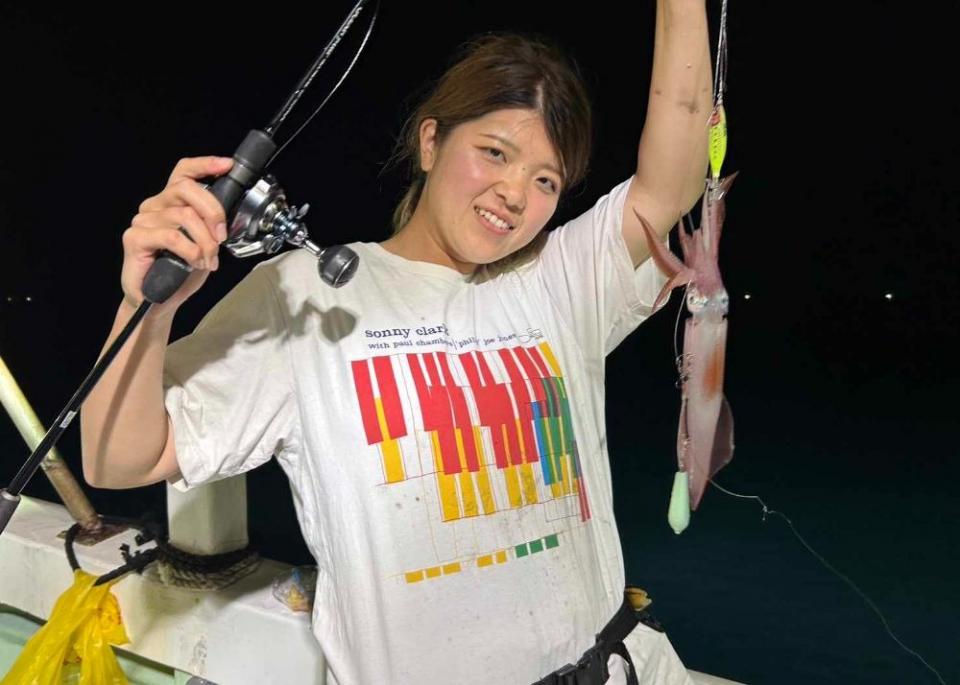 写真：釣り上げたイカを笑顔で掲げている女性ライター