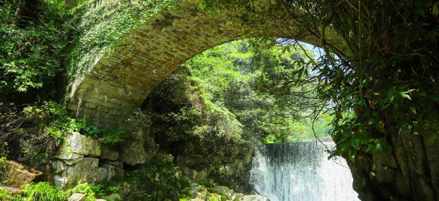 写真：眼鏡橋を下から見上げる風景。橋の奥に堰から流れ落ちる水が見える