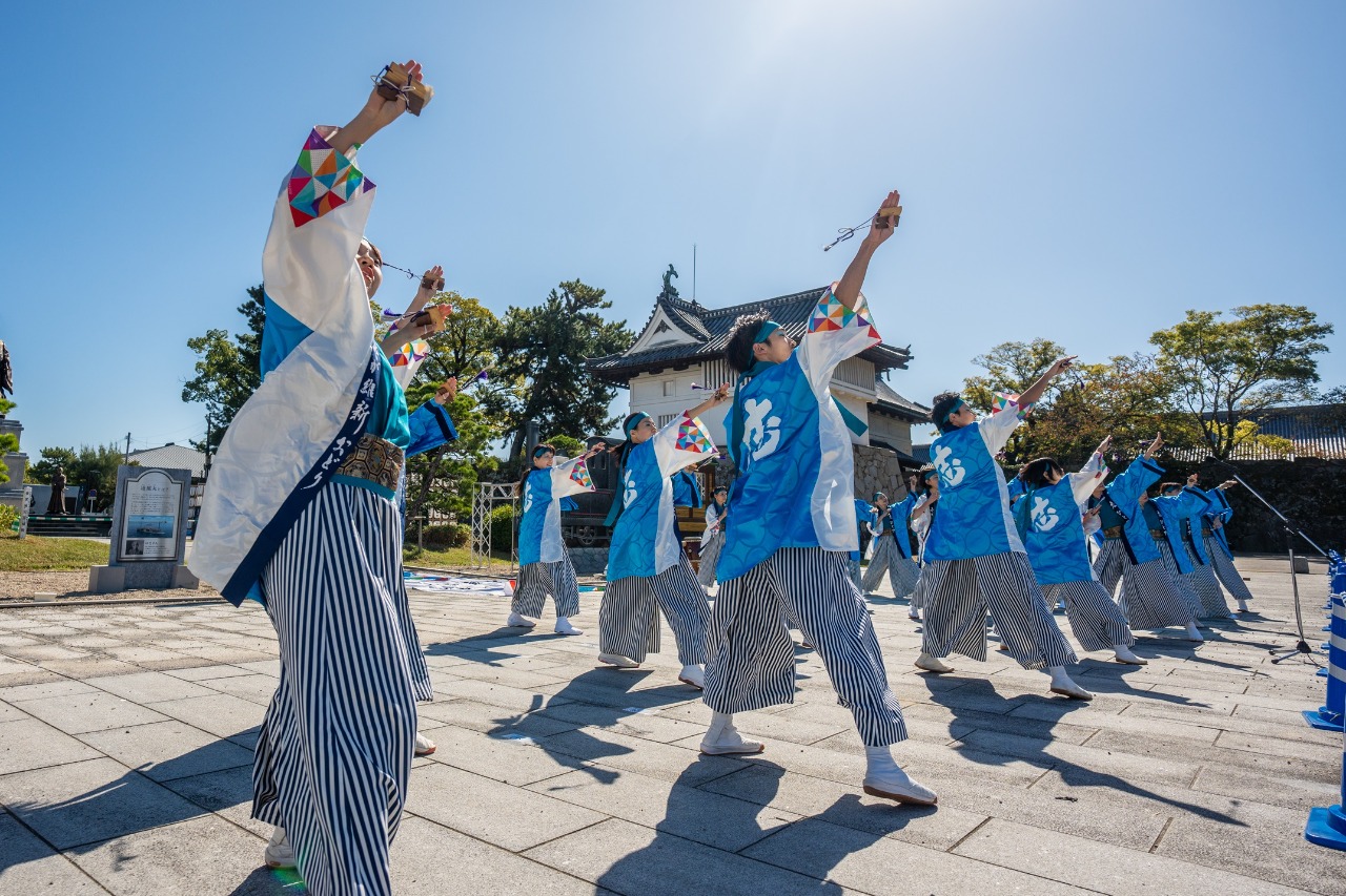 写真：法被と袴の衣装をつけたおどり隊が城内エリアの広場で踊っている様子