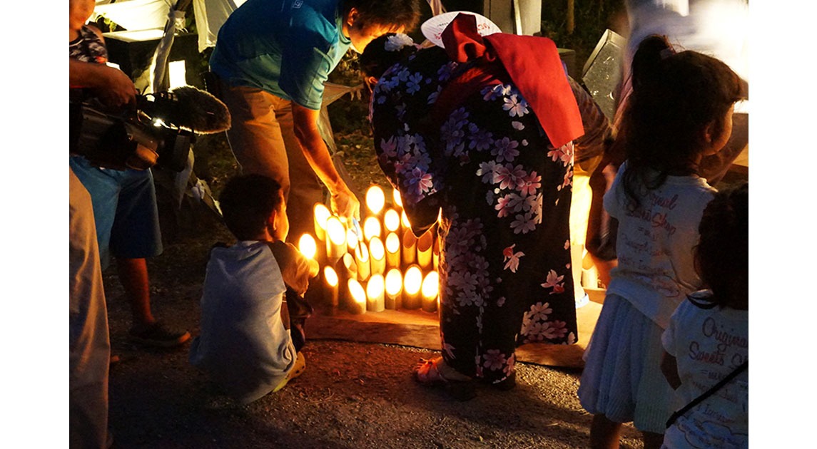 写真：肥前浜宿土曜夜市の様子。街角に設置された竹灯籠を浴衣姿の女性や子供たちが眺めている