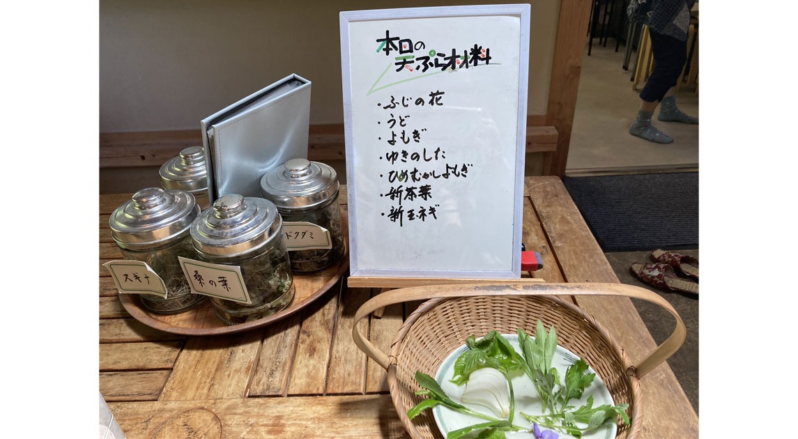 写真：かごに盛った天ぷら用の食材と、茶葉の瓶詰めがテーブルの上に並んでいる様子