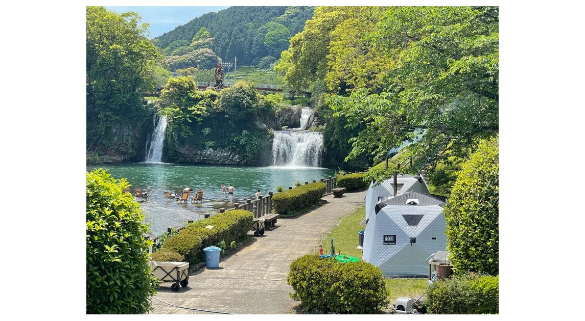 写真：川岸にテントサウナが並んでいる風景。奥に滝が流れ落ちている