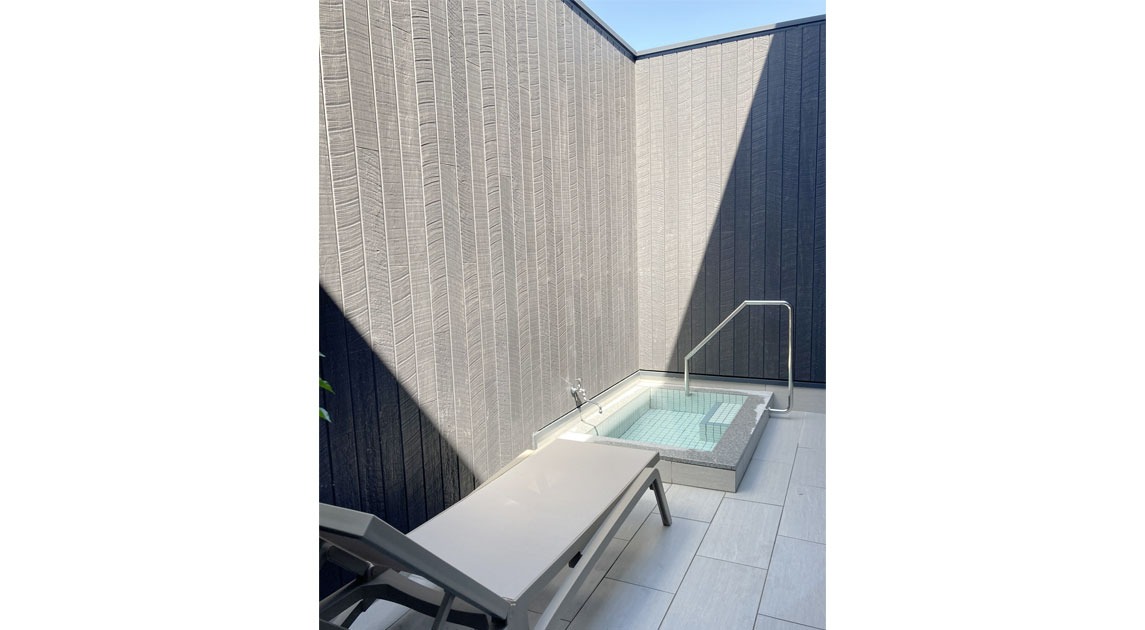 写真：浴室から続いている露天スペース。木製の塀に囲われており、外から見えないように配慮されている。水風呂とカウチがある