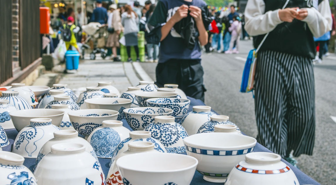 写真：店舗前に設置した商品棚にたくさんの茶碗が並べられている様子。遠景は買い物客でにぎわっている