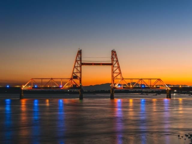 写真：夕刻の筑後川昇開橋。ライトアップが川面に写り込んでいる