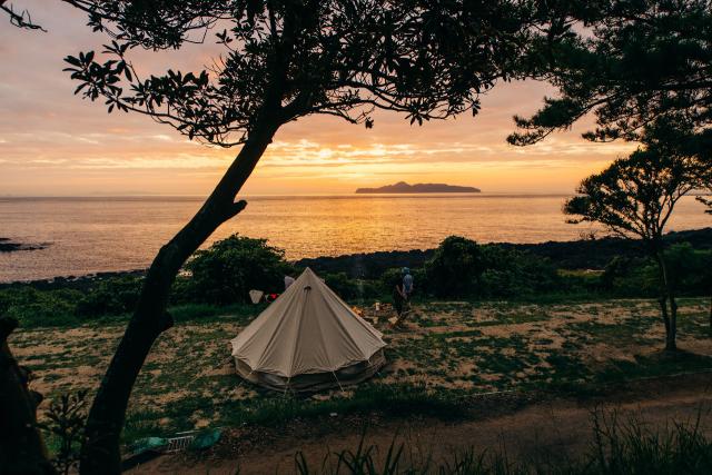 写真：夕日が沈む海の前のテント