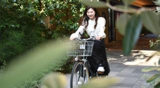 写真：自転車に乗っている女性。背景にカラエの建物が見える