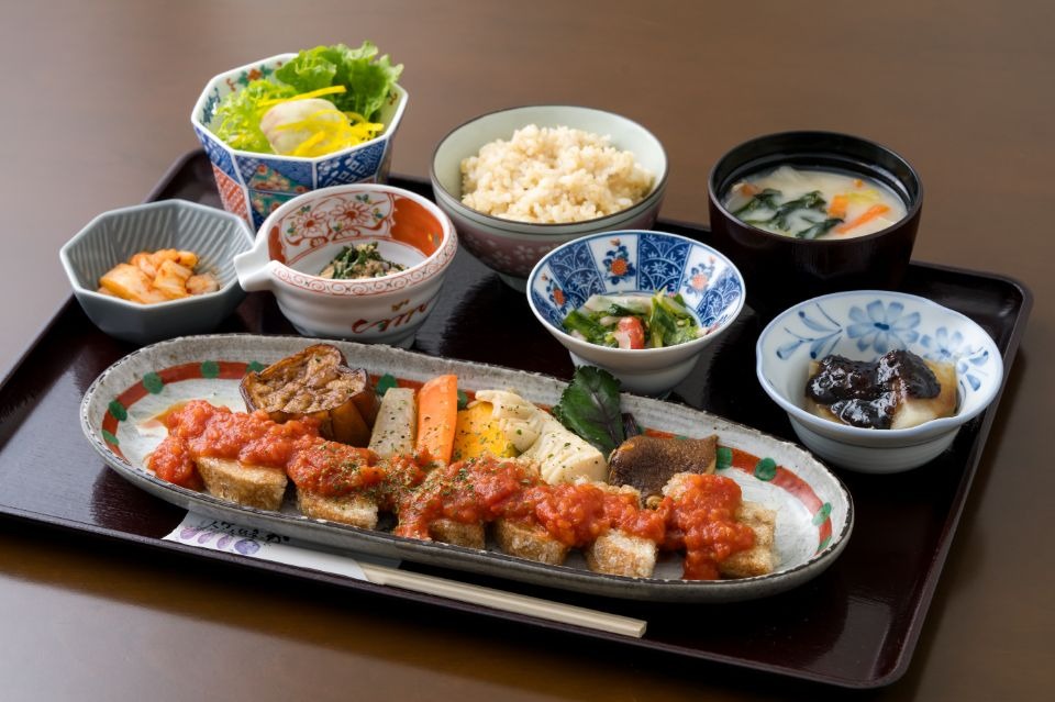 黒いお盆の上に、くるまふを焼いたものとご飯、味噌汁、複数の小鉢が並べられた料理画像