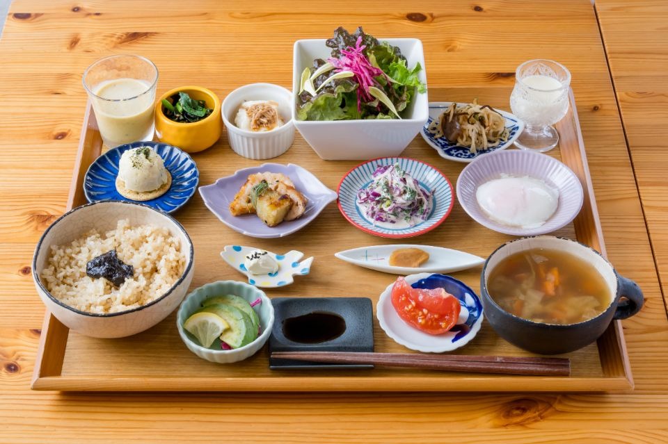 木製のお盆の上に豆皿に盛られた野菜料理が複数と、ご飯が並んだ料理画像